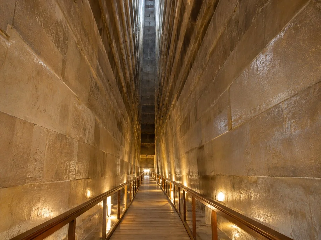 Die hoë korbeel-Groot Galery binne die Groot Piramide, verlig deur sagte lampe langs ’n steil houtlooppad